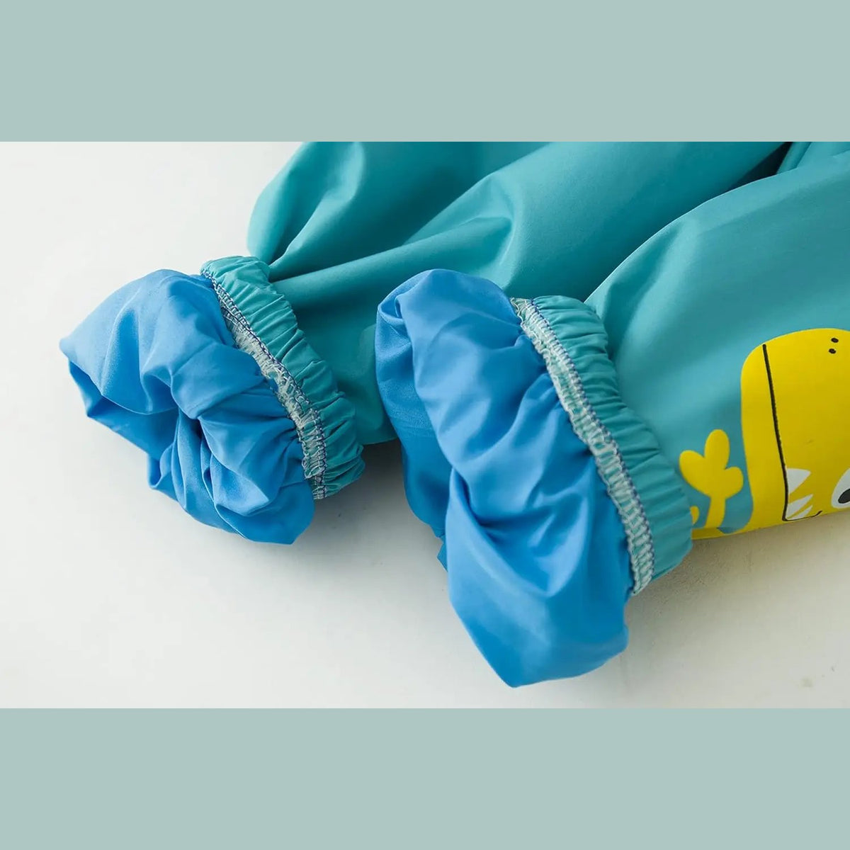 Kinder-Regenanzug mit Kapuzenjacke und Hose in Blau mit Dinosaurier-Motiv und in Rosa mit Einhorn-Motiv